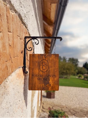 Dřevěná cedule s logem svatební stodoly Pod správným vrchem zavěšená na kovové konzoli